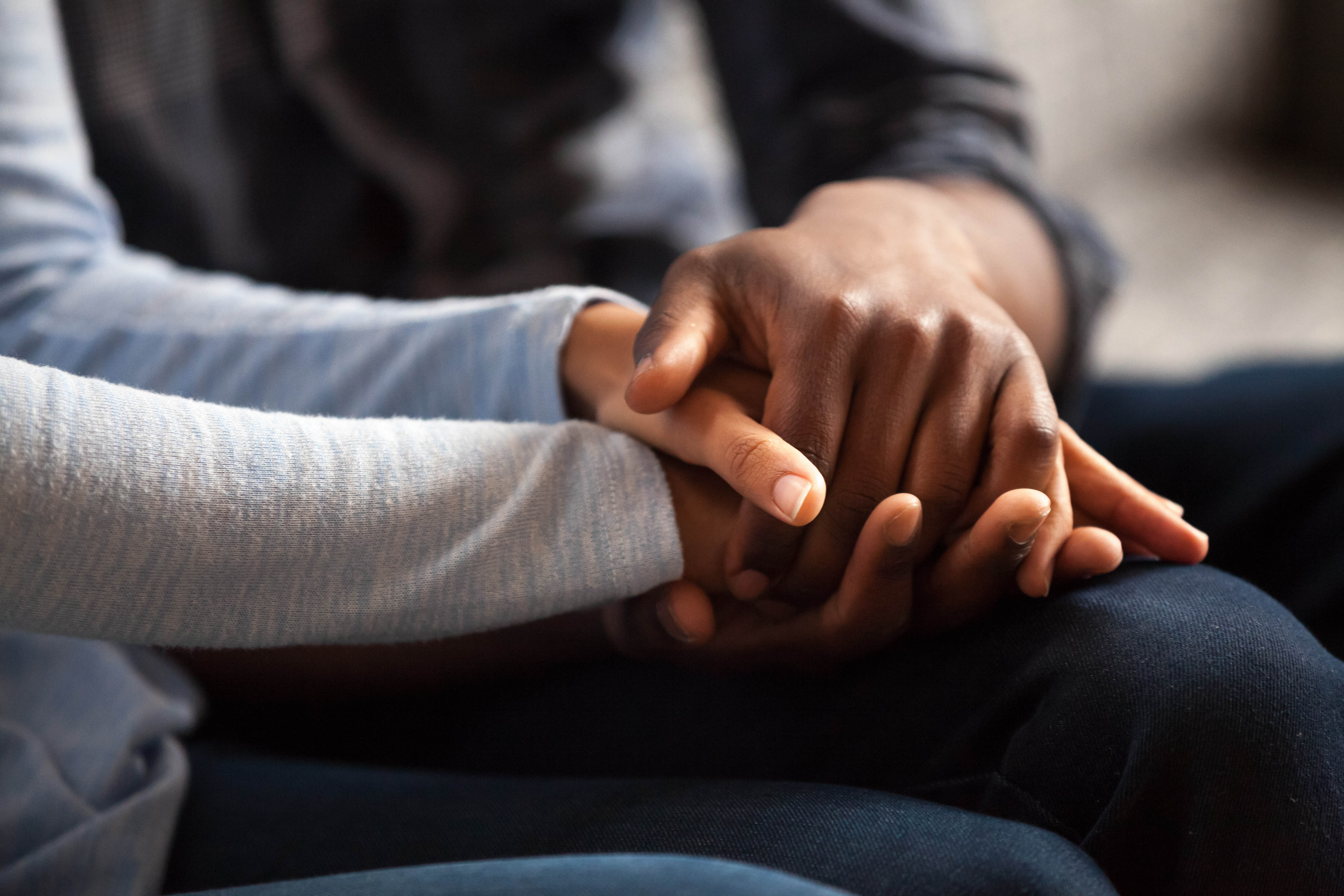 Close-up of couples hands while sitting getting bad news in a doctor's office